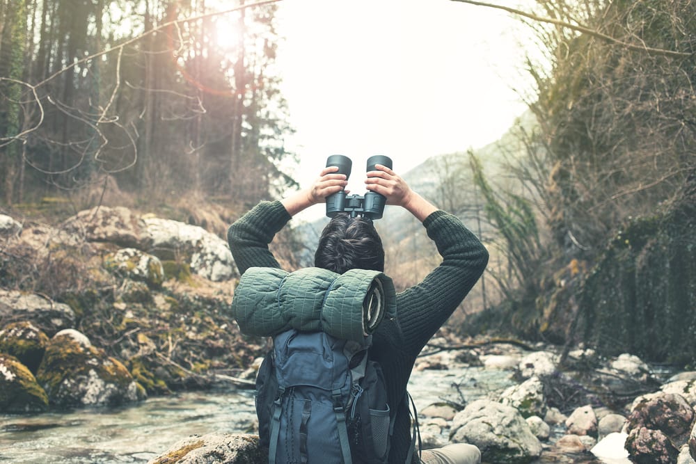 man in nature looks through binoculars